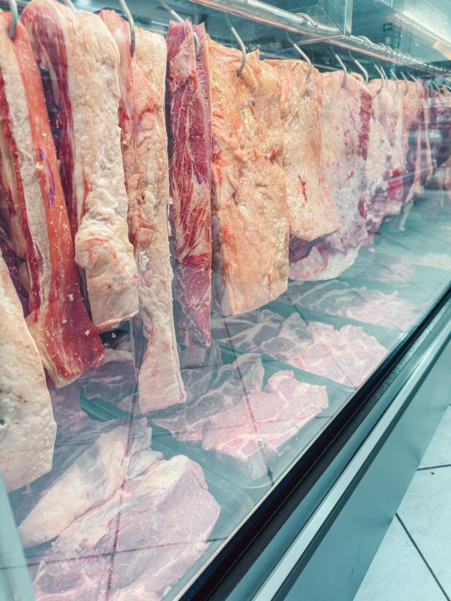 Peças de carne penduradas no expositor do açougue